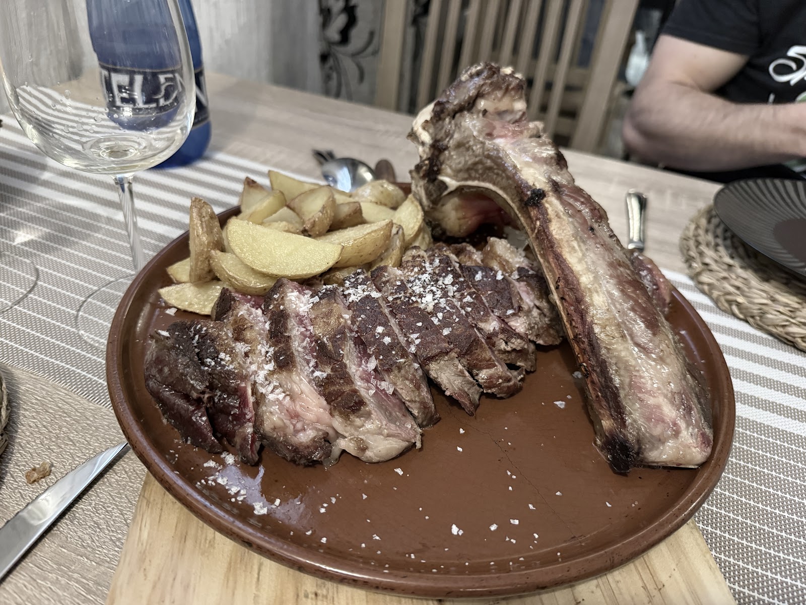 Costilla de cerdo asada, cortada en porciones jugosas, acompañada de papas doradas.