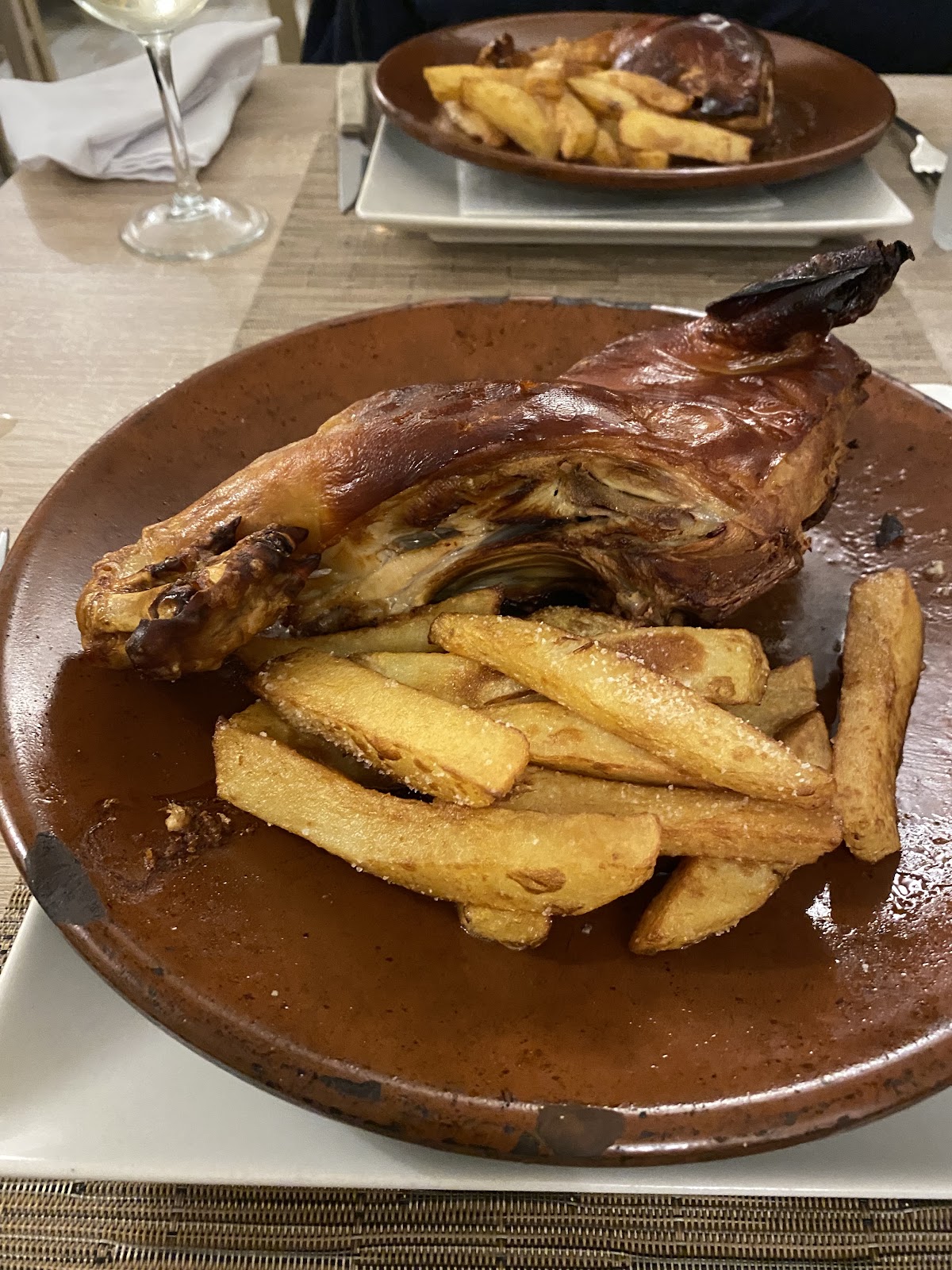 Pernil de cerdo asado con piel crujiente y dorada, servido con patatas fritas.
